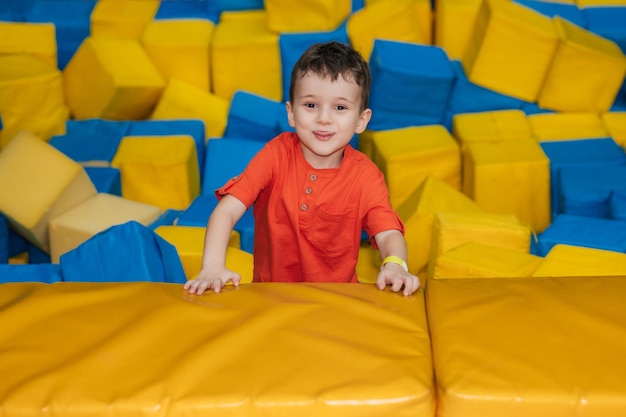 Un bambino gioca in una piscina con cubi morbidi Un bambino in una stanza per bambini di intrattenimento di gioco