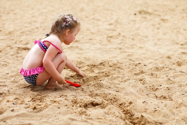 Un bambino gioca nella sabbia. Bella ragazza seduta sulla spiaggia.