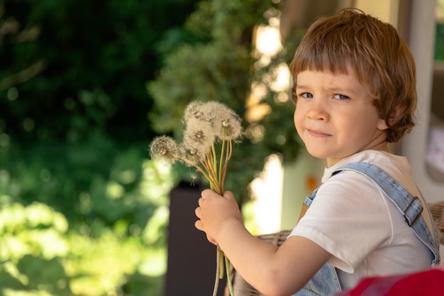 Un bambino in età prescolare tiene i denti di leone seduti accanto al trailer