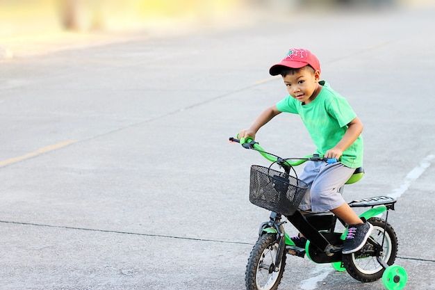 Un bambino in sella a una bicicletta con ruote di addestramento.