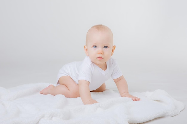 Un bambino in un body bianco striscia su uno sfondo bianco