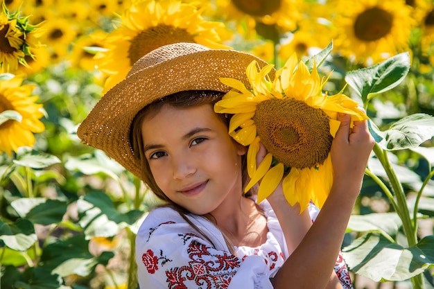 Un bambino in un campo di girasoli con una camicia ricamata. Concetto di festa dell'indipendenza dell'Ucraina. Messa a fuoco selettiva.