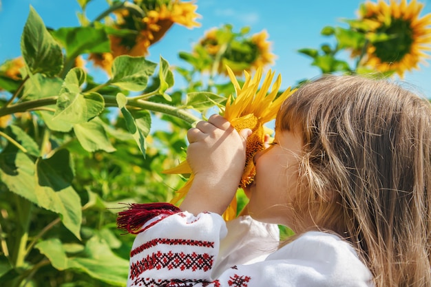 Un bambino in un campo di girasoli in una camicia ricamata.