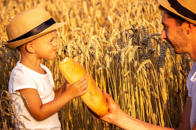 Un bambino in un campo di grano mangia il pane. Natura. messa a fuoco selettiva