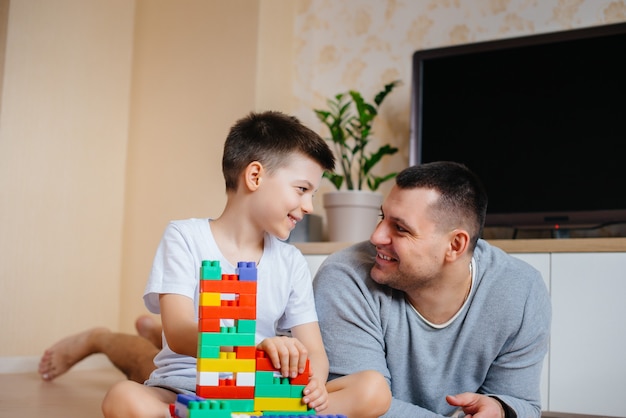 Un bambino insieme a suo padre è interpretato da un costruttore e costruisce una casa. Costruzione di una casa di famiglia.