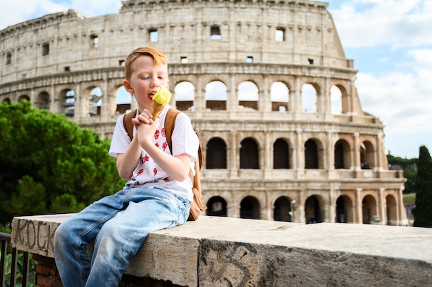 Un bambino mangia il gelato sul Colosseo. Italia, Roma