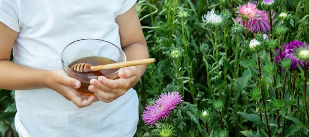 Un bambino mangia il miele in un giardino fiorito. Natura. Messa a fuoco selettiva