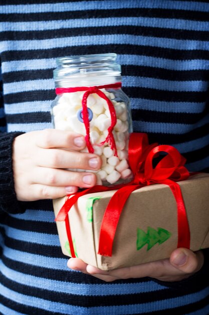 Un bambino per dare regali di Natale e una banca di un pupazzo di neve con marshmallow