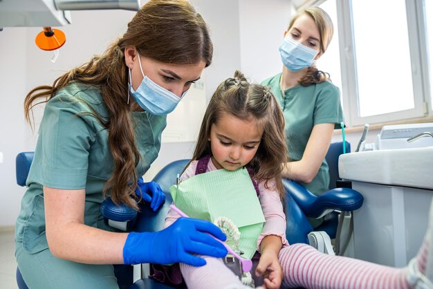 Un bambino piccolo all'appuntamento dal dentista il dottore mostra e racconta come lavarsi i denti