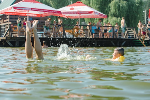 Un bambino piccolo che nuota nel lago con le braccia gonfiabili aiuta il supporto
