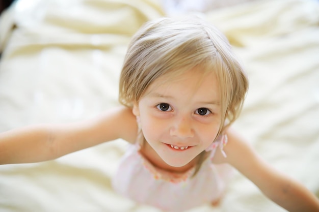 Un bambino piccolo con i capelli biondi giace sul letto Bambina sta giocando sul divano