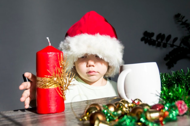 Un bambino piccolo con un cappello di babbo natale con doni al tavolo di capodanno