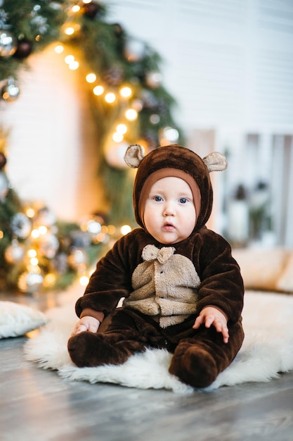 Un bambino piccolo con un costume da orsacchiotto marrone si siede sul pavimento