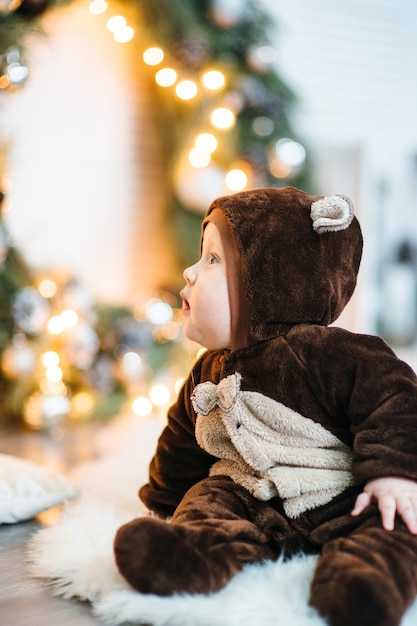 Un bambino piccolo con un costume da orsacchiotto marrone si siede sul pavimento