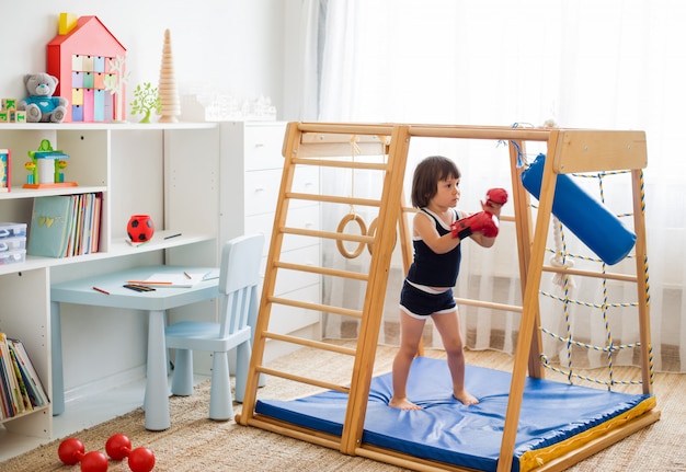 Un bambino piccolo è impegnato nella boxe in un complesso sportivo di casa in legno.