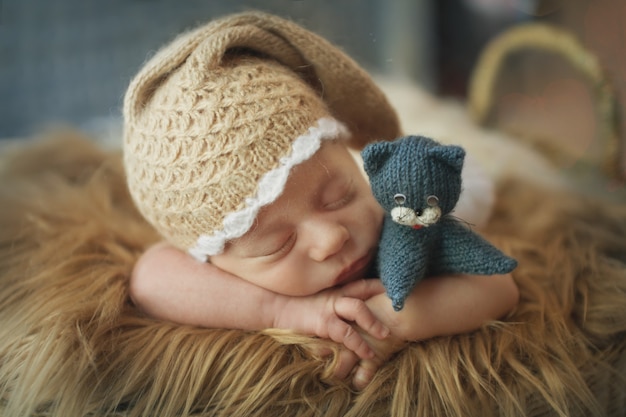 Un bambino piccolo in una cesta dorme in un caldo cappello lavorato a maglia con un pompon