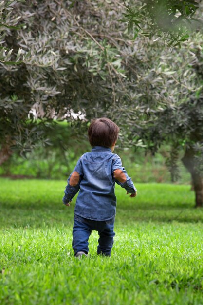 un bambino piccolo sta camminando sull'erba e indossa una giacca