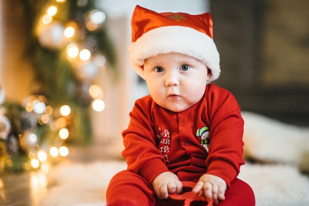 Un bambino piccolo vestito di rosso si siede sul pavimento