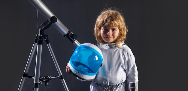 Un bambino piccolo vuole volare nello spazio indossando un casco da astronauta con un telescopio copia spazio astrono...