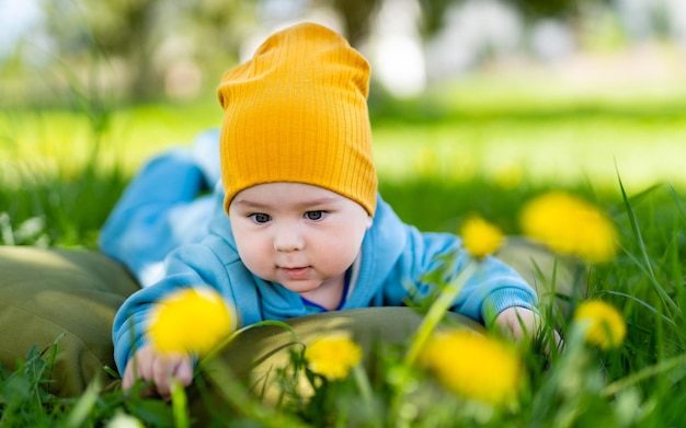 Un bambino sdraiato nell'erba con un cappello giallo un bambino carino con un capcello giallo sdraiato sull'erba