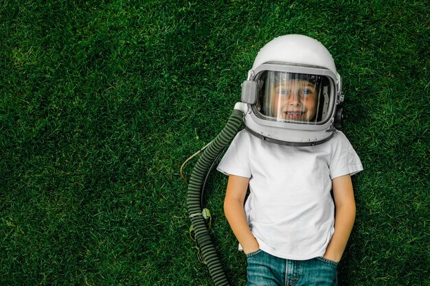 Un bambino sdraiato sull'erba indossa il casco di un astronauta e sogna grandi traguardi!