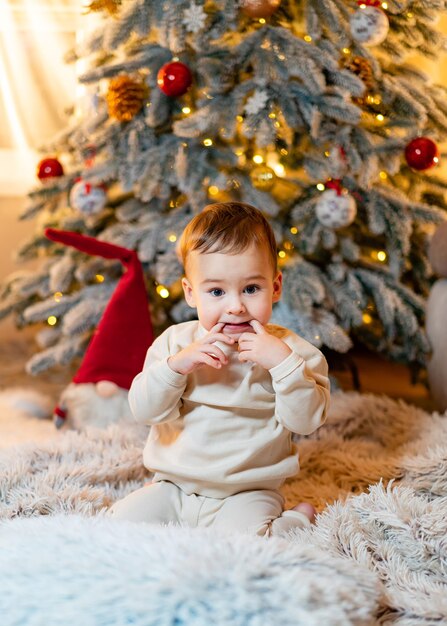 Un bambino seduto davanti a un albero di Natale