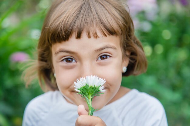 Un bambino sente l'odore di un fiore nel giardino Messa a fuoco selettiva