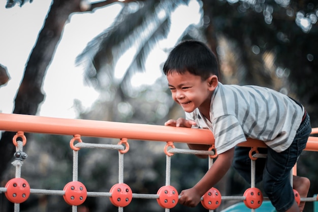 Un bambino si arrampica su una griglia alpina in un parco in un parco giochi in una calda giornata estiva parco giochi per bambini in un parco pubblico animazione e svago per bambini