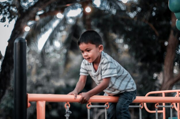 Un bambino si arrampica su una griglia alpina in un parco in un parco giochi in una calda giornata estiva parco giochi per bambini in un parco pubblico animazione e svago per bambini
