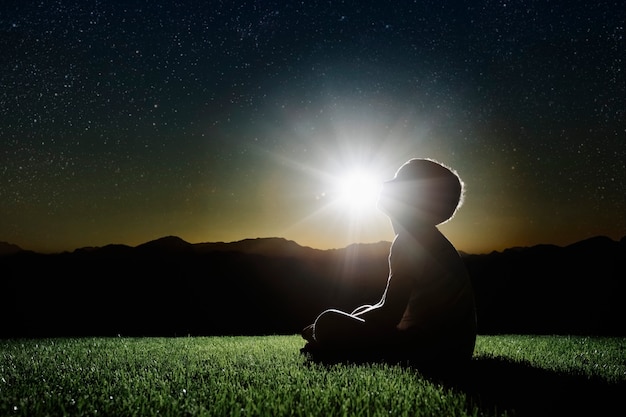 Un bambino si siede sulla cima di una montagna al tramonto e sogna