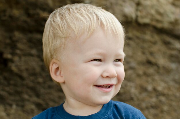 Un bambino sorridente del ragazzino è un ritratto biondo del primo piano all'aperto