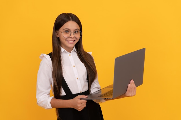 Un bambino sorridente in uniforme scolastica e occhiali studia sulla sindrome da visione del computer portatile