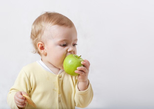 Un bambino sta cercando di mangiare il suo primo spuntino. Spazio libero per un testo