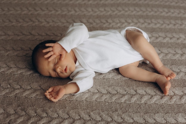 un bambino sta dormendo su un tappeto con una camicia bianca