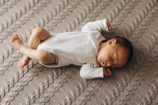 un bambino sta dormendo su una coperta con una camicia bianca