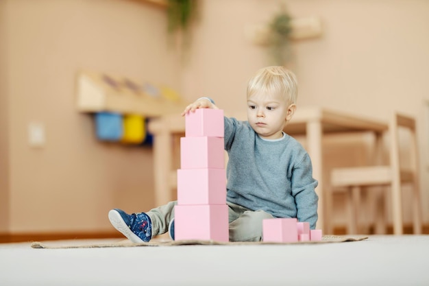 Un bambino sta giocando con i giocattoli educativi all'asilo, sta costruendo una torre di blocchi