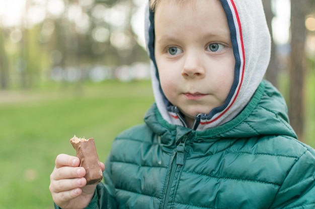 Un bambino sta mangiando una barretta di cioccolato nel parco