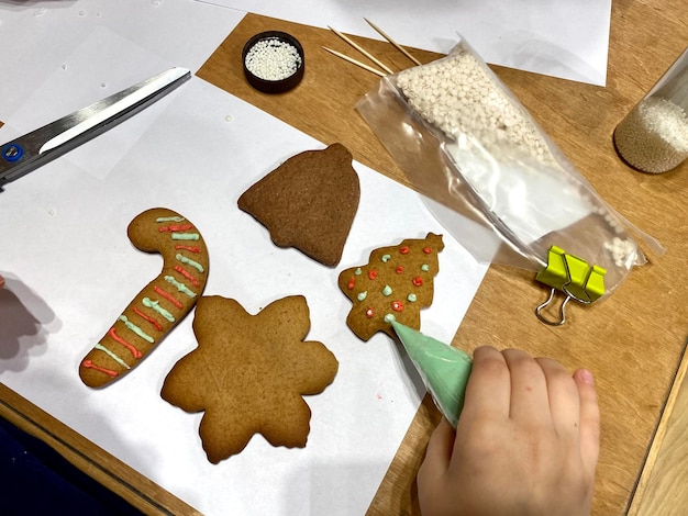 Un bambino sta preparando biscotti di pan di zenzero con un albero verde e un paio di forbici.