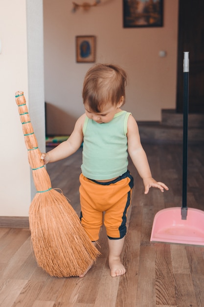 Un bambino sta pulendo la casa. La ragazza spazza il pavimento. ripristino dell'ordine nell'appartamento