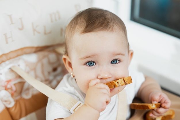 Un bambino su un seggiolone che mangia un cracker con uvetta