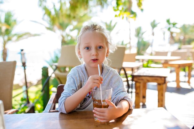 Un bambino sulla spiaggia beve cocco Messa a fuoco selettiva