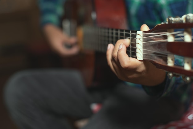 Un bambino suona la chitarra classica. dettaglio sulle dita del mono sinistro che crea un accordo