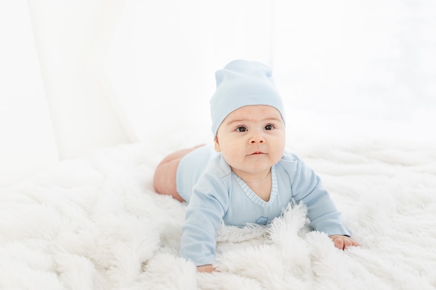 Un bambino vestito di blu è sdraiato a pancia in giù su un tappeto bianco