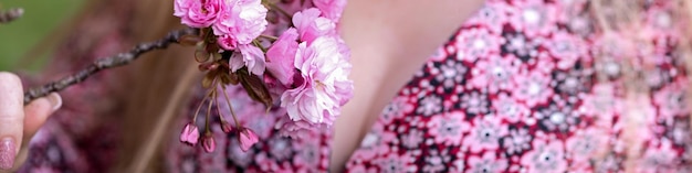 Un banner 4x1 per i social network e un sito web Una bella ragazza tiene in mano un rametto di fiori di ciliegio