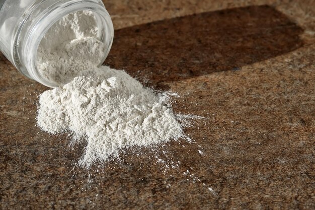 Un barattolo aperto di scrub powder per il viso sparsi su una piastrella