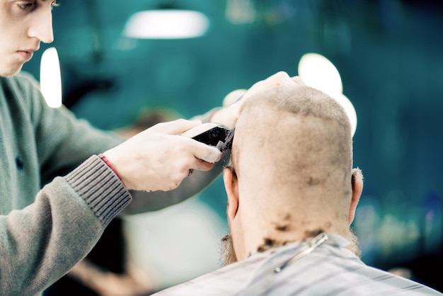 Un barbiere maschio che fa un taglio di capelli calvo a un uomo