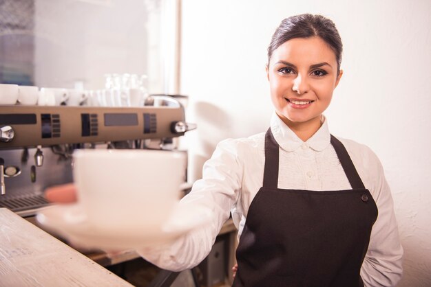 Un barista piuttosto giovane offre una tazza di caffè in un bar.