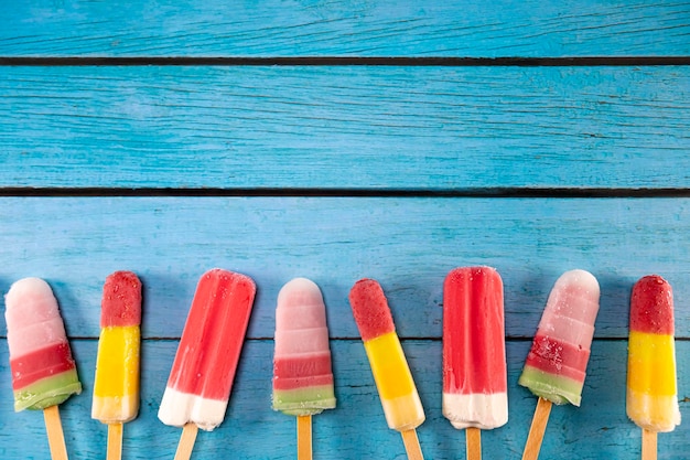 Un bastone di gelato di frutta colorato sembra fresco da mangiare posto su un legno blu vintage