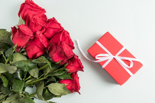 Un bel bouquet di rose rosse e una confezione regalo su sfondo bianco vista dall'alto Concetto di regalo