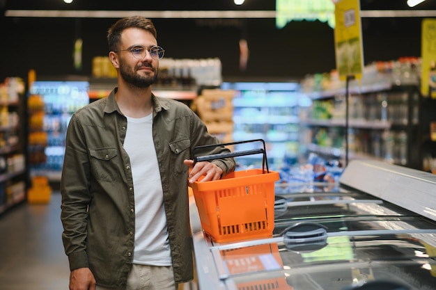 Un bel giovane che sceglie cibo al supermercato.